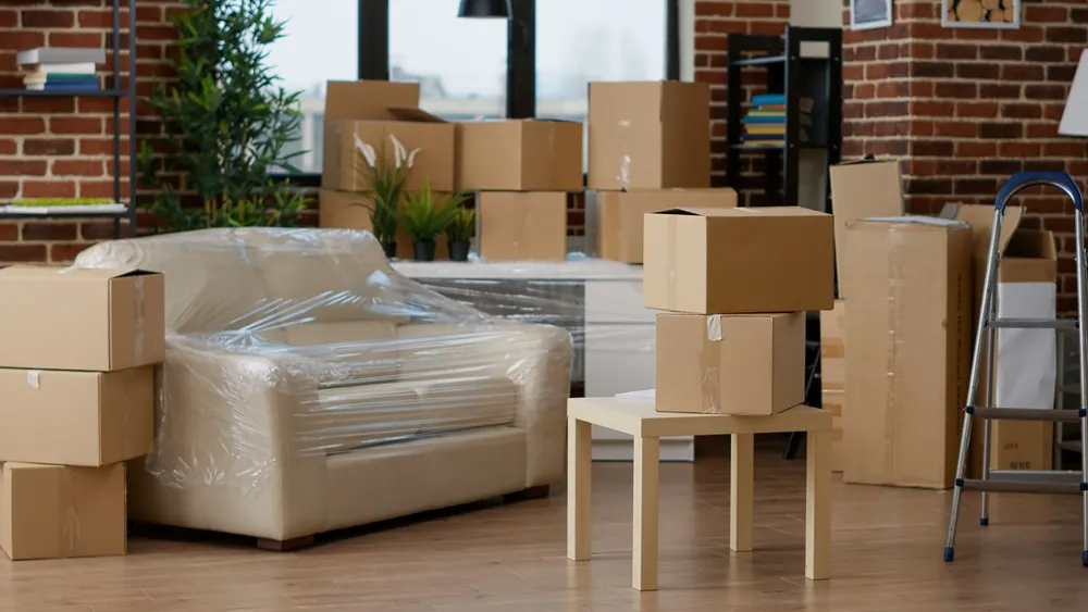 Salon encombré de cartons et de mobilier emballé avant débarras